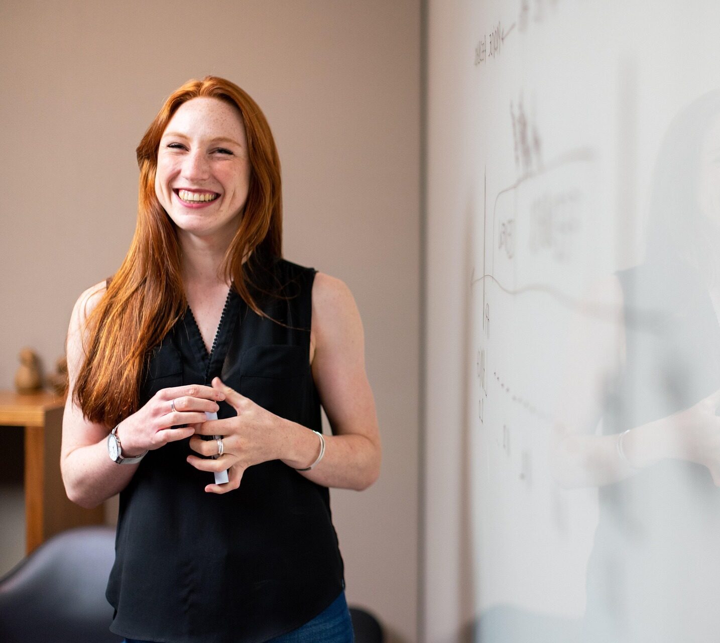 Decorative: woman standing in front of a white board smiling